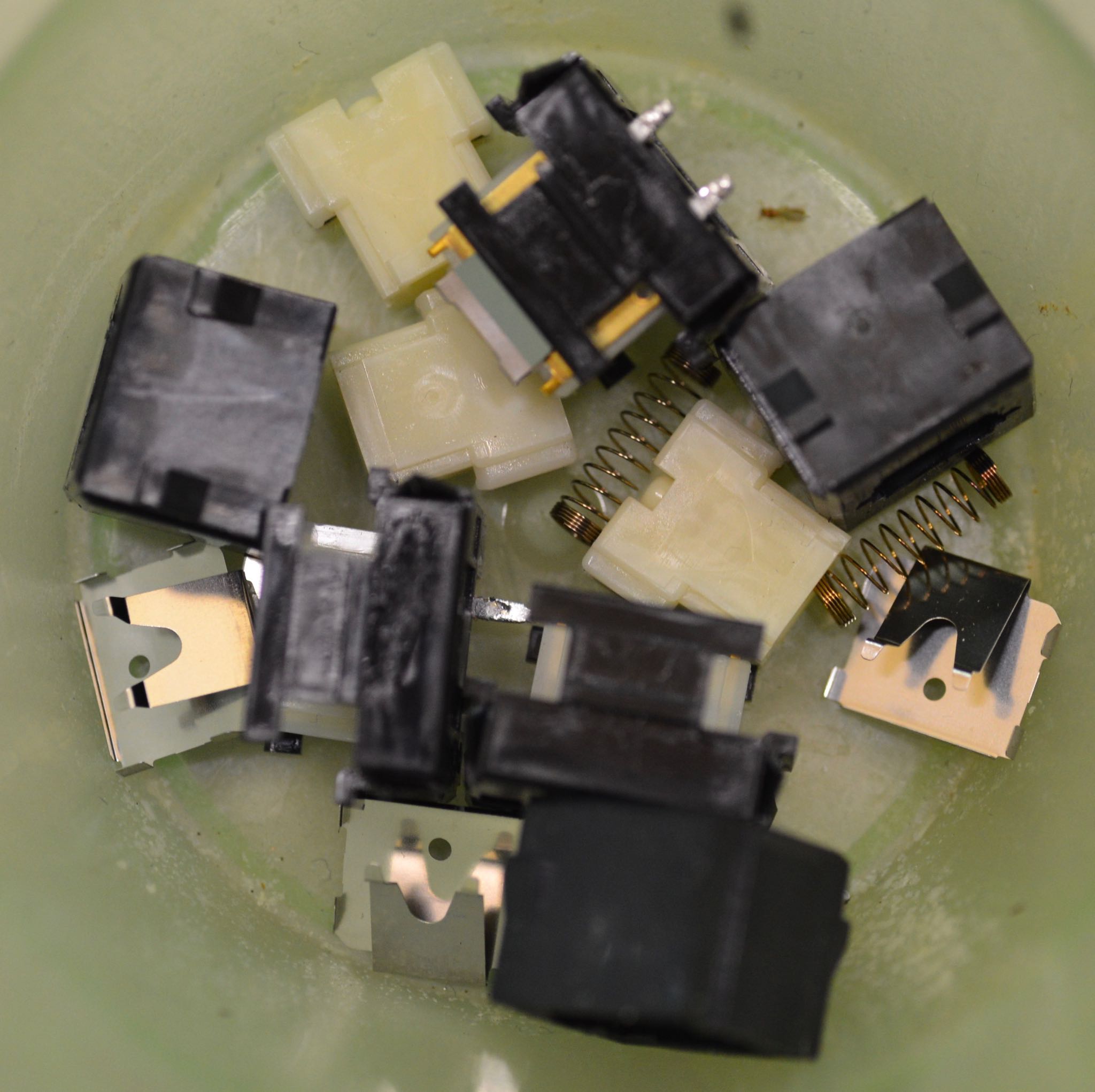 Switches disassembled. Switch plates remain in lower housing. Upper housing, click leaf, slider, and spring are separate.